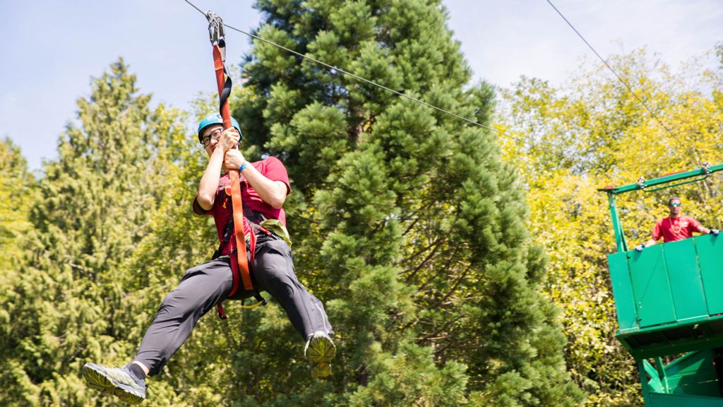 A rider in a helmet and harness sailing down the zip line at a past Cool August Nights